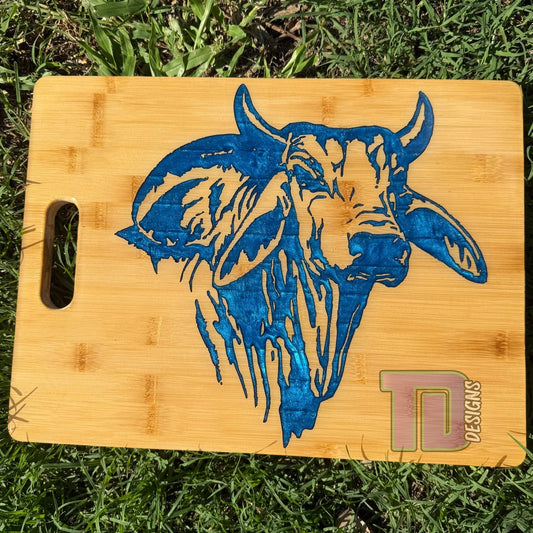 Bamboo cutting board with blue bull design on grass