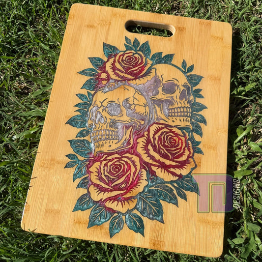 Wooden cutting board with skull and rose design on grass