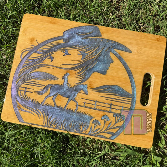 Wooden cutting board with engraved design of a horse and rider on grass