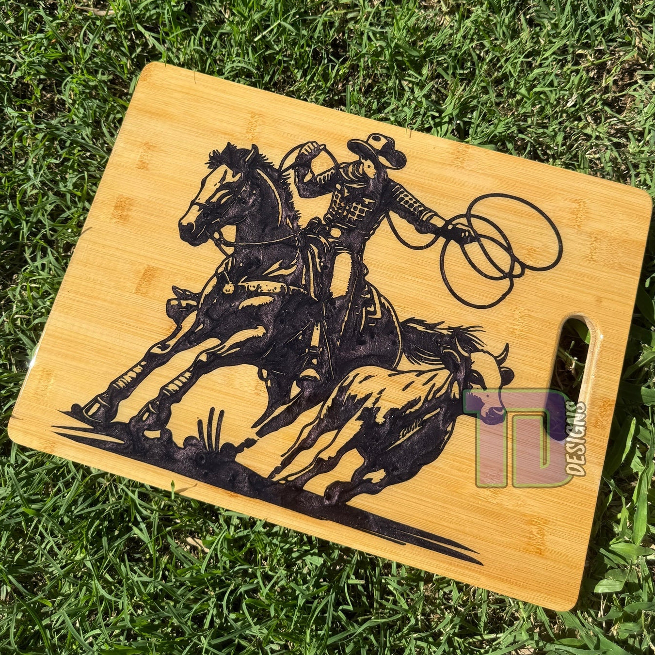 Wooden cutting board with a horse and rider design on grass