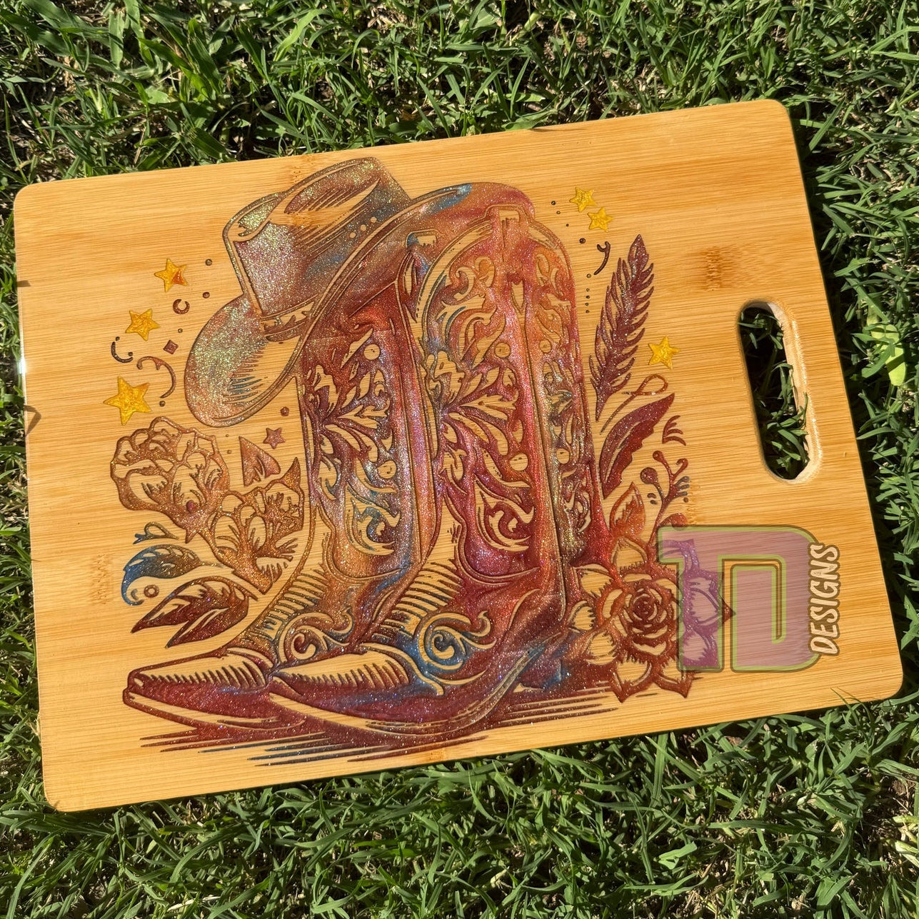 Wooden cutting board with cowboy boot and hat design on grass